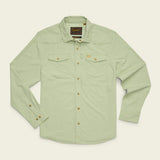 The Howler Brothers Emerger Tech Longsleeve, a light green UPF shirt designed for sun protection, features two chest pockets, buttoned cuffs, and a branded patch on the inside collar. It is displayed laid flat on a light background.