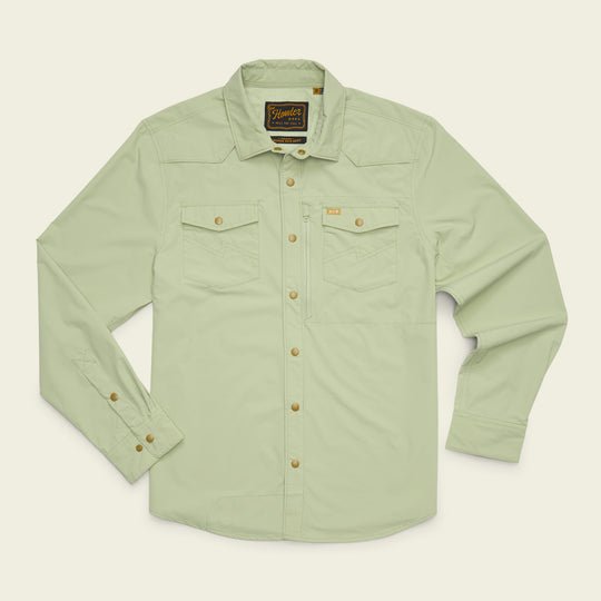 The Howler Brothers Emerger Tech Longsleeve, a light green UPF shirt designed for sun protection, features two chest pockets, buttoned cuffs, and a branded patch on the inside collar. It is displayed laid flat on a light background.