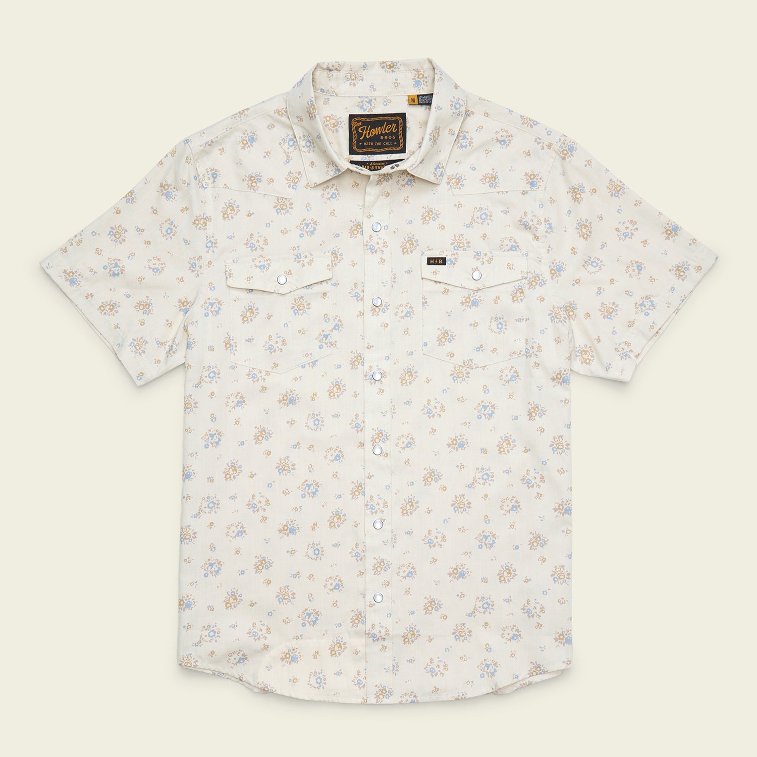 The Howler Brothers H Bar B Snapshirt by Howler Brothers is a short-sleeved, button-up shirt featuring pearl snaps, a light floral pattern, two chest pockets, and a collar, displayed on a plain background.