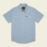 The Howler Brothers H Bar B Snapshirt is a light blue, short-sleeve button-up featuring two chest pockets, subtle vertical stripes, and a branded tag on the left pocket. Designed with classic pearl snaps for easy fastening, this shirt offers quick-drying comfort all day long.