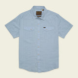 The Howler Brothers H Bar B Snapshirt is a light blue, short-sleeve button-up featuring two chest pockets, subtle vertical stripes, and a branded tag on the left pocket. Designed with classic pearl snaps for easy fastening, this shirt offers quick-drying comfort all day long.