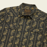 A dark button-up technical utility shirt with a yellow floral stripe pattern, featuring two chest pockets with flaps, pearl snaps for added style, and a “Howler Brothers” label on the inside collar.