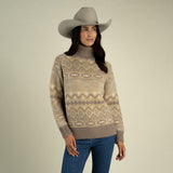 A person wearing a wide-brimmed grey hat and a tan and brown patterned Shiloh Sweater by Sendero Provisions Co. with ribbed cuffs.
