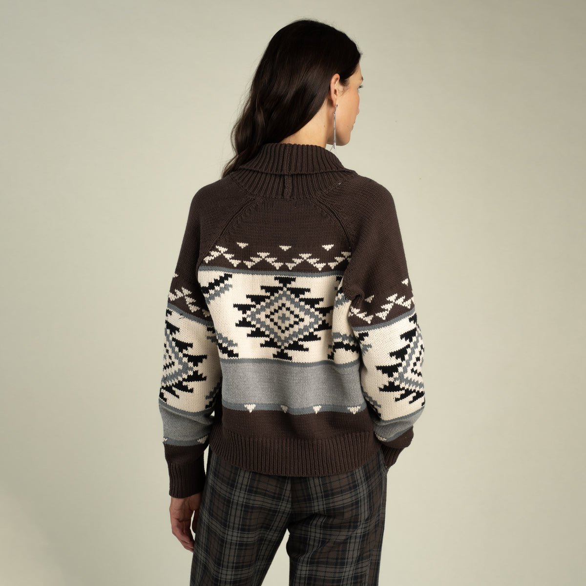 Back view of a person wearing a Cimarron Cardigan, a button-front, brown, white, and gray knit cardigan featuring a geometric southwestern-inspired pattern and a shawl collar.