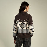 Back view of a person wearing a Cimarron Cardigan, a button-front, brown, white, and gray knit cardigan featuring a geometric southwestern-inspired pattern and a shawl collar.