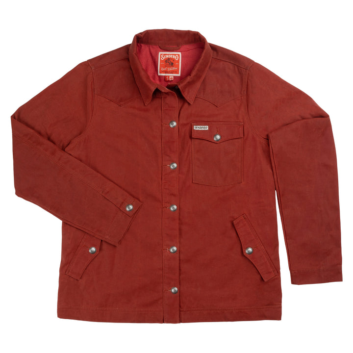 The Women’s Rancho Waxed Jacket by Sendero Provisions Co. is crafted from water-wicking waxed cotton canvas and features a rust color, button-up front with silver buttons, collared neckline, western-style chest pocket flaps, and two front pockets. The jacket is displayed flat on a white background.