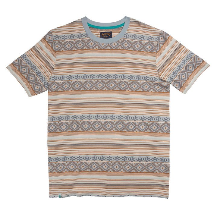 The Bisbee Jacquard Tee by Sendero Provisions Co. is a short-sleeve T-shirt featuring Southwest-inspired horizontal geometric patterns in beige, blue, and orange tones. Crafted from textured cotton jacquard in a classic fit, it is pictured laid flat on a white background.