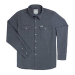 The Stamford Work Shirt Concho Blue by Sendero Provisions Co. is a long-sleeve, button-up denim shirt in a rich blue shade, featuring two front chest pockets, a collar, and classic pearl snap closures. The shirt is shown laid flat on a white background.