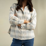 A woman wears the Sendero Helena Button Down, a relaxed fit light blue and white plaid cotton western shirt detailed with small bird embroidery.