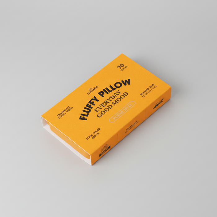 A closed rectangular orange box of “Fluffy Pillow Incense Sticks | Collins” by Collins, labeled with “Everyday Good Mood,” contains 70 sugar-colored sticks. Made with natural ingredients, the box rests on a light gray surface.