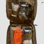 The CoveyKits Molle Kit- Working Dog First Aid Kit by CoveyKits is an open tan pouch containing essential survival and first aid supplies for pets, such as honey packets, a small comb, bandages, and various small items secured with elastic straps—perfect as a portable pet first aid kit for emergency dog care or basic wound treatment on the go.