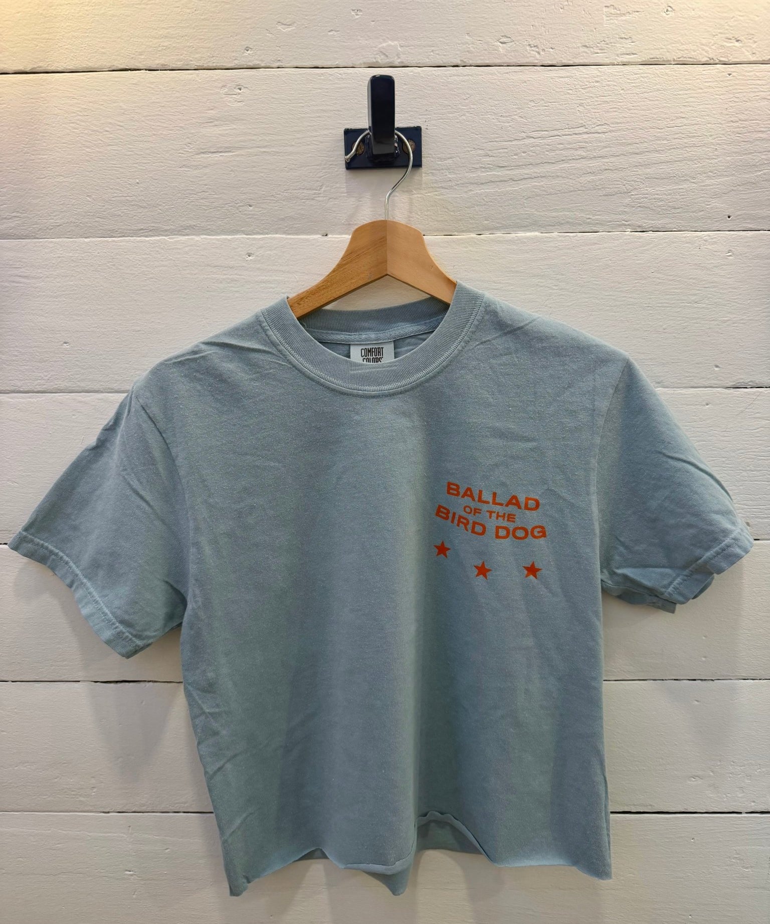 Small Town Revival Crop Ballad of the Bird Dog yankey blue cropped t-shirt with “Ballad of the Bird Dog” and three orange stars printed on the chest.