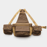 The Duck Camp Canvas Upland Strap Vest by Duck Camp is shown on a plain white background, featuring a brown and tan design with three compartments, adjustable beige straps inspired by classic field gear, and secure snap button closures.