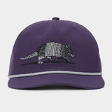 The Armadillo Hat by Duck Camp is a purple 5-panel cap with a stylish grey rope detail above the brim, featuring an embroidered armadillo on the front and an adjustable snapback for a comfortable fit.