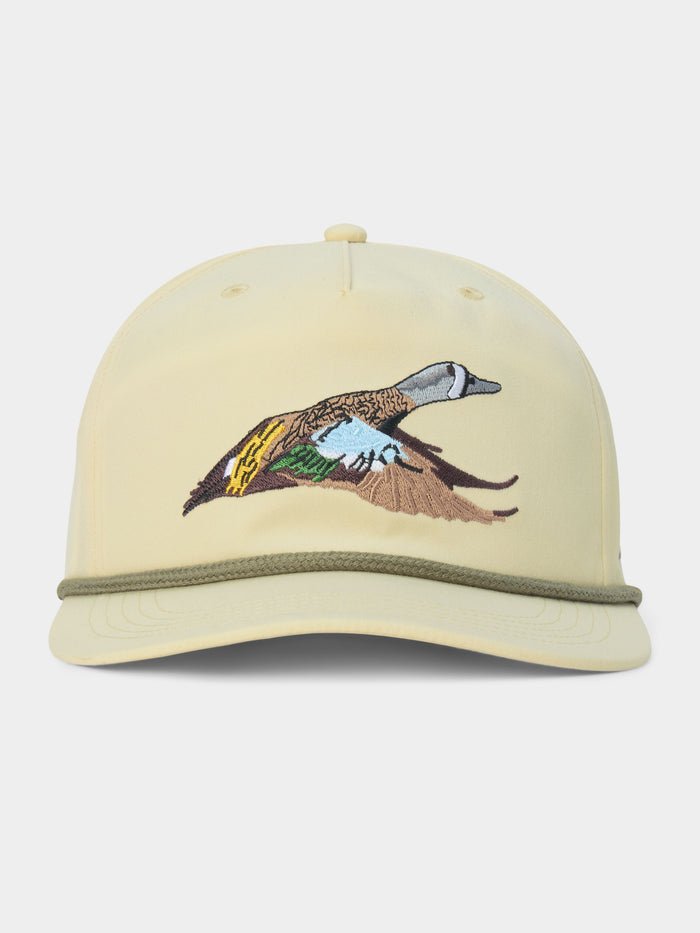 Introducing the Duck Camp Blue Winged Teal Hat by Duck Camp—a beige baseball cap accented with a green cord above the brim and an embroidered duck in flight on the front panel. This adjustable hat is crafted for comfort and style, making it perfect for any outdoor adventure.