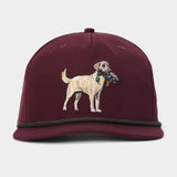 The Yellow Lab Hat by Duck Camp is a maroon 5-panel cap featuring an embroidered image of a dog holding a bird in its mouth on the front, designed with an adjustable fit for comfort.