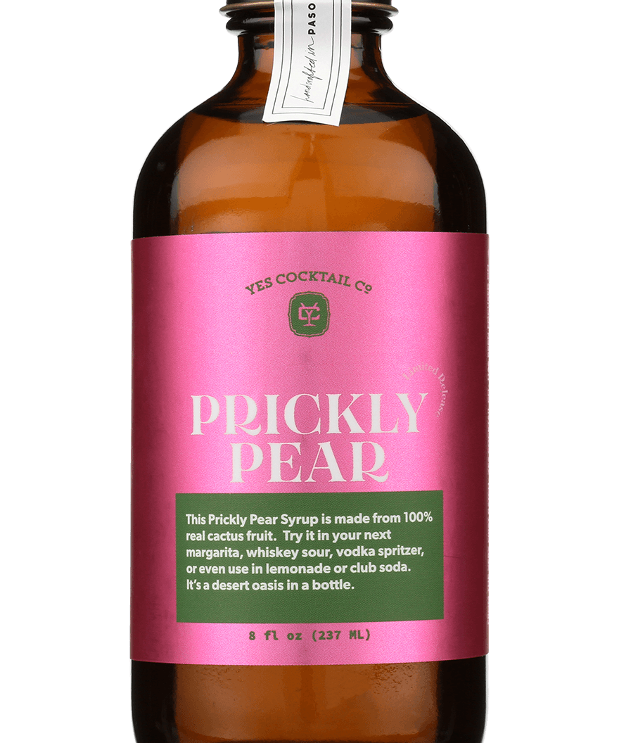 A brown glass bottle with a pink label reading "Prickly Pear Syrup | Yes Cocktail Co" contains a vibrant syrup made from real prickly pear juice, perfect for cocktails, crafted by Yes Cocktail Co.