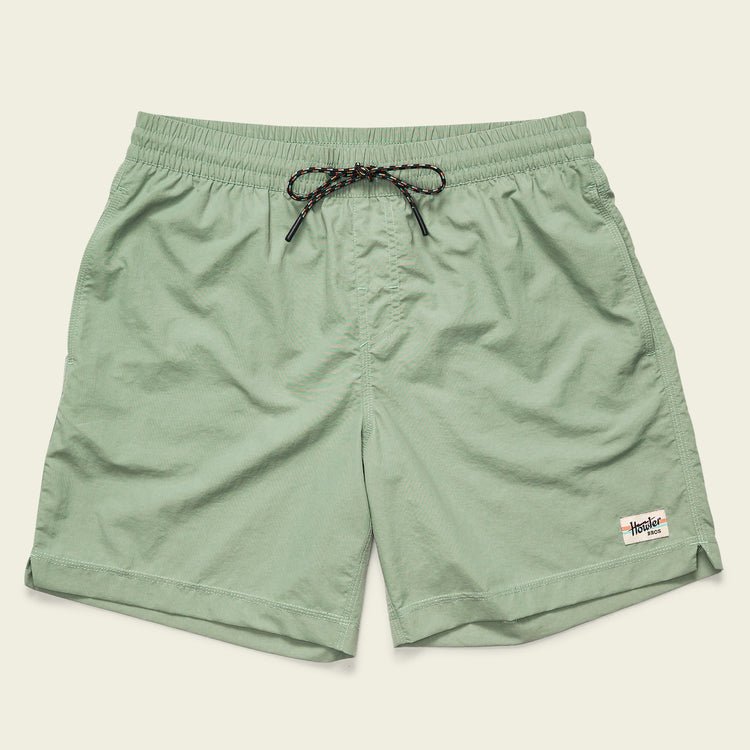 The Salado Shorts by Howler Brothers are light green men’s quick-drying nylon shorts with an elastic waistband, black drawstring, side pockets, and a small white rectangular logo patch on the left hem.