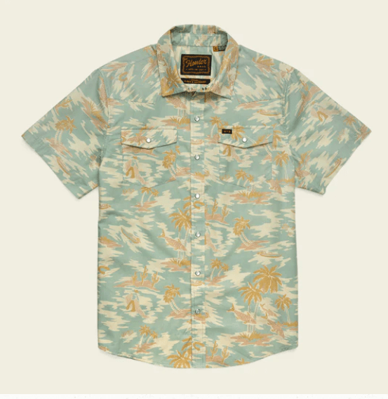 The Howler Brothers H Bar B Snapshirt features a light green and beige tropical palm print, classic pearl snaps, and two chest pockets with button flaps. Inspired by timeless H Bar B style.