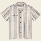 The Howler Brothers Shores Club Shirt features a vintage textured weave, camp collar, short sleeves, vertical beige, white, and gray stripes, two chest pockets, and brown buttons—ideal for spring 2026. Laid flat on a light background.