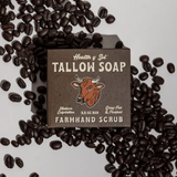 A box of Health y Sol Tallow Soap from Health y Sol, Farmhand Scrub variety, made with all-natural ingredients, is displayed on a white surface with scattered coffee beans.