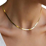 A person wears the Zoe Gold Snake Chain Necklace by Peter and June around their neck, paired with a white top visible at the shoulder.