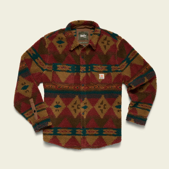 The Allegheny Fleece by Howler Brothers is a long-sleeve button-up overshirt in high pile fleece, featuring an earthy-toned multicolored geometric pattern, shown flat on a beige background.