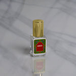 A small Nemat Amber Perfume Oil bottle with a gold cap and red label rests on marble, ready to reveal its subtle amber fragrance as your new signature scent.