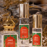 Three bottles of Nemat Amber Perfume Oil, each with gold and silver caps, are displayed on a surface. The subtle personal scent is highlighted, with dried flowers softly blurred in the background.
