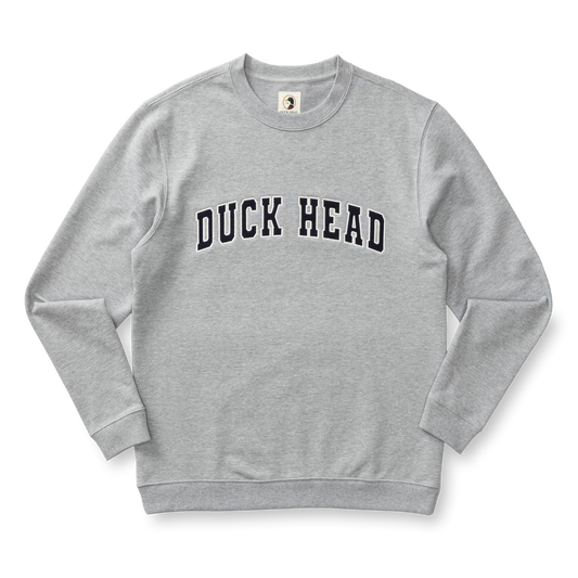 The Duck Head Applique Crewneck Sweatshirt is a light gray cotton crewneck with vintage-style ribbing and bold "DUCK HEAD" lettering across the chest.