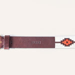 The ATX Dark by Zilker Belts is a hand-stitched Argentine leather belt with a gold buckle, "ZILKER" embossing, and red and white geometric accents at one end.
