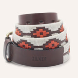 The ATX Dark by Zilker Belts is an Argentine leather belt with "ZILKER" embossed on the tip, hand-stitched white and red geometric embroidery, and a brass buckle.
