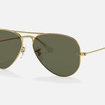 The Ray-Ban 3025 Aviator sunglasses feature gold frames and dark green lenses, highlighting the iconic pilot style against a plain light background.