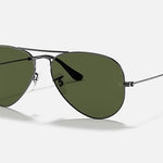 The Ray-Ban 3025 Aviator sunglasses feature a classic pilot shape with dark green lenses and a sleek black metal frame, shown on a white background.