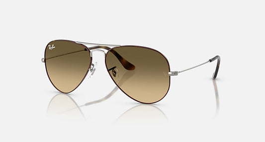 Ray-Ban Aviator | Large Metal sunglasses featuring brown-tinted gradient black lenses, a thin metal frame, and curved arms are displayed on a white background.