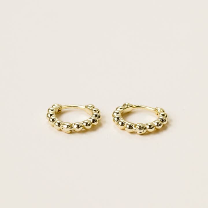 The JaxKelly Ball Hoop - Tiny - Gold Earrings are 18K gold plated with a beaded design, hypoallergenic, and shown on a light-colored background.