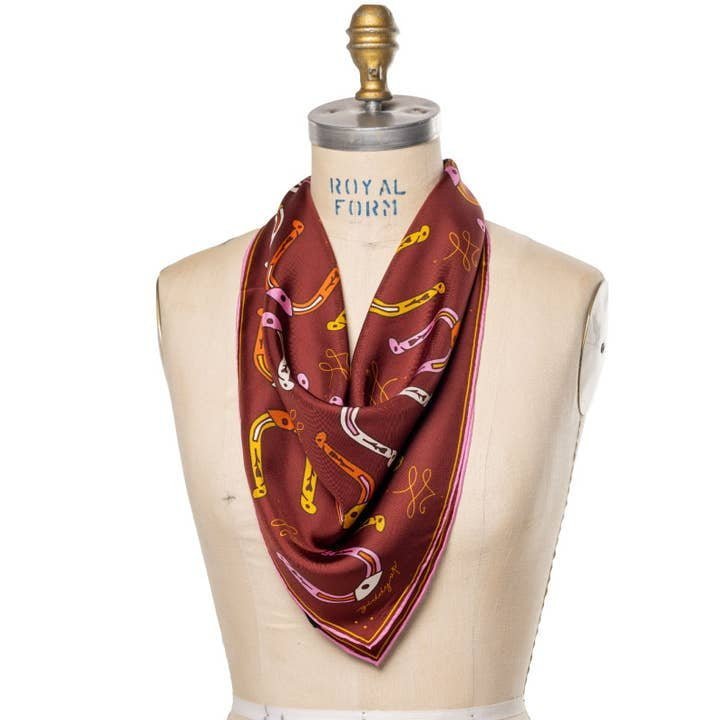 The Bandana | Big Horseshoe by Jenni Earle, featuring a hand-illustrated design and delicate edging, is draped around the neck of a dress form labeled “Royal Form.”.