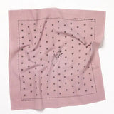 The "Chin Up Buttercup" bandana by Jenni Earle is a square pink cotton bandana with a central hand-holding-flowers line drawing, dotted border, and repeating floral pattern inspired by classic western styles.