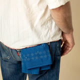 A person in a white shirt and blue jeans has a Jenni Earle "Hell Yeah" bandana sticking out of their back pocket.