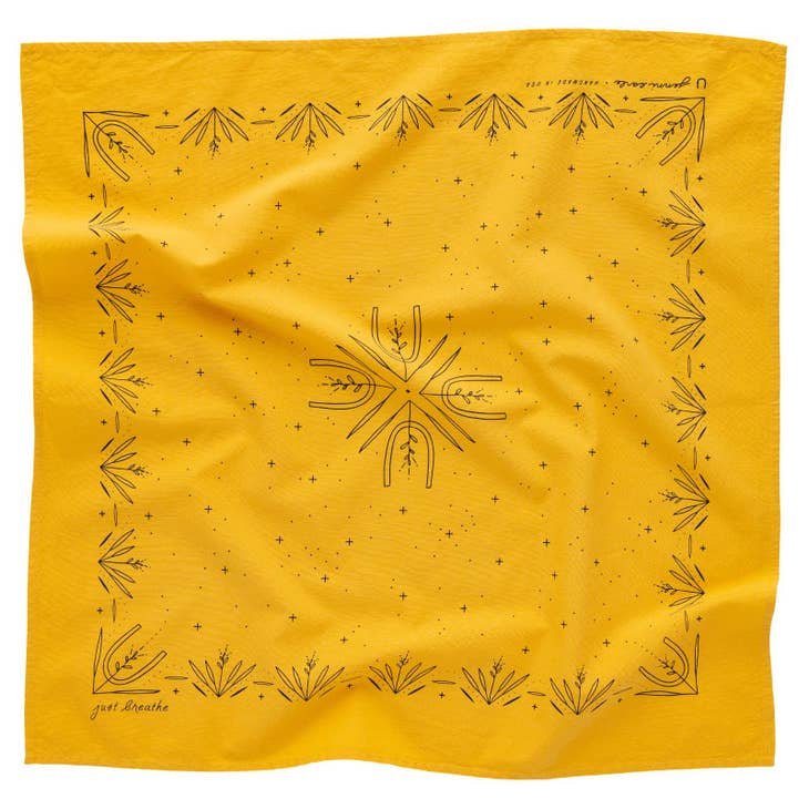 The "Just Breathe" bandana by Jenni Earle is yellow, hand-dyed, and features a black geometric and botanical pattern with a central symmetrical design and decorative border elements.