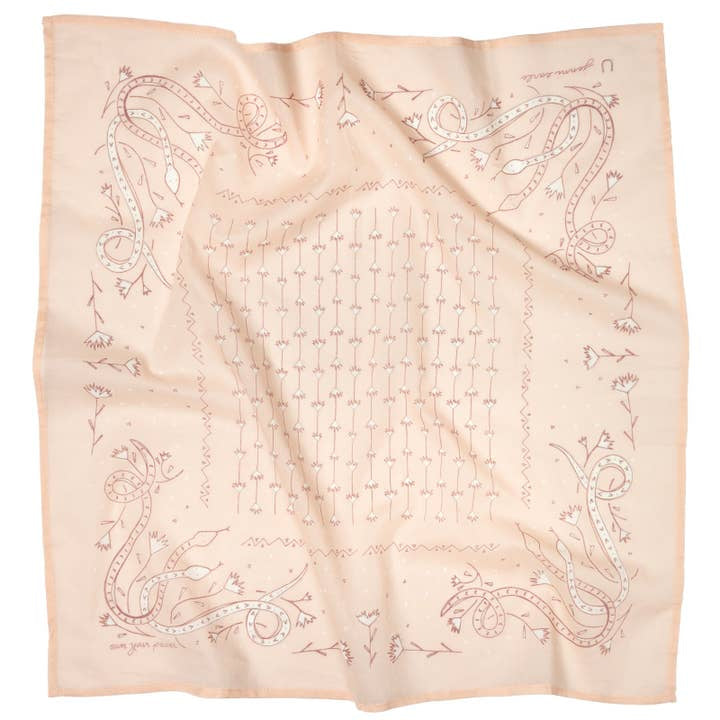 The Jenni Earle “Own Your Power” Bandana features a light pink square with hand drawn snakes, flowers, and geometric patterns in muted brownish-red on luxury cotton fabric. Slightly wrinkled for a handcrafted touch.