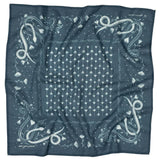 The "Own Your Power" Bandana by Jenni Earle is square and blue, featuring white dandelions at the center and stylized snakes and gladiolus in each corner, finished with a patterned border—ideal for expressing personal power.