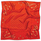 The Bandana | Own Your Power Silk by Jenni Earle features poppy red silk with a floral center and four stylized snakes in beige and gold at the corners. Its unique, slightly wrinkled texture makes it a standout holiday gift.