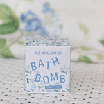 A box of Old Whaling Co. Bath Bombs in the Floral Coast scent rests on a white woven surface, with soft hydrangea notes and a subtle floral backdrop.