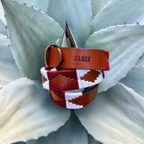 The Big Bend by Zilker Belts, crafted from hand-stitched Argentine leather and featuring a geometric "ZILKER" pattern, rests atop a pale green agave plant.