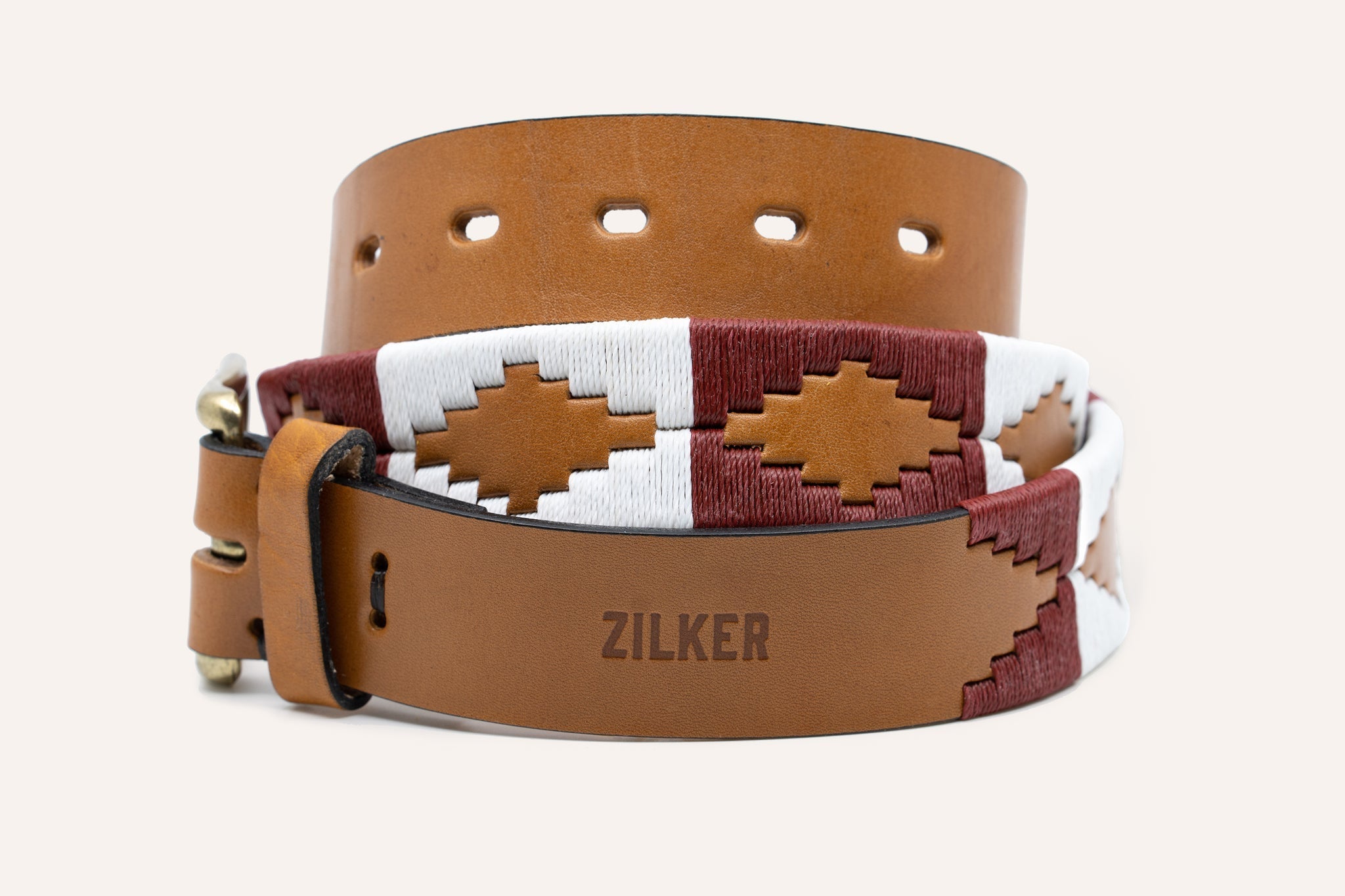 The Big Bend by Zilker Belts is a brown Argentine leather belt with "ZILKER" engraved and red, white, and beige hand-stitched geometric embroidery.