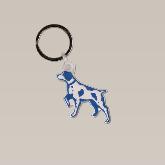 The Bird Dog Keychain by Sticker Mule features a blue and white dog-shaped silicone pendant on a metal keyring—ideal as an outdoorsman gift or stylish accessory.
