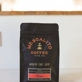 A black bag of Mescalito Coffee's Blend Whole Coffee Beans | Chilcon rests on a counter, with a blurred indoor background.