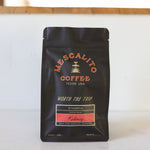 A black bag of Mescalito Coffee's Blend Whole Coffee Beans, Kalimaz, stands on a white surface, emphasizing bold flavors of dark chocolate and raspberry—a testament to the unique character of Ethiopian beans.