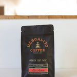 A black bag of Mescalito Coffee labeled "Blend Whole Coffee Beans | San Antonio" from Texas, USA, featuring Pacamara beans with anaerobic fermentation, sits on a white surface.